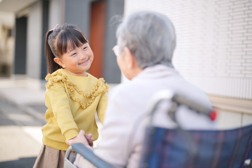 女の子とおばあちゃんが笑顔で仲良く手を繋いでいる写真。